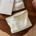 Detail of off-white lace embroidery makeup bag with simple wish label on a table - Organza Paisley Embroidery / Organza Paisley