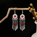 Bohemian silver earrings featuring vibrant red and turquoise beads with long tassels - Red
