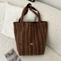 Detail of a brown shearling tote bag featuring dark vertical stripes and a gold logo plate - Brown and Green Stripes