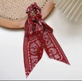 Coletero rojo con estampado paisley y cintas largas sobre una bandeja de mimbre tejido - Rojo