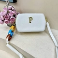 Detail van een witte crossbodytas met gouden P-logo en kleurrijke schakelketting - Wit