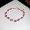 Detailed view of pink oval zircons set in a gold chain bracelet with adjustable lobster clasp - Gold-Pink