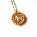 Detailed close-up of a Virgin Mary pendant with orange bead border on a gold bead chain - Orange