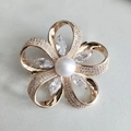 Dettaglio di una spilla a fiore dorata con perla bianca e zirconi cubici in micro-pave - Oro Zircone Bianco