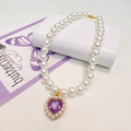 Macro detail of elegant pearl pet collar with a purple heart crystal pendant and gold clasp - Purple