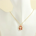 Detailed close-up of a Christmas gift box pendant with red enamel bow on a gold necklace - Gift Box