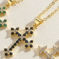 Dettaglio macro del ciondolo a croce placcato oro con zirconi colorati sulla collana - Zircone Nero