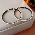 Detalle de pendientes de aro grandes en blanco y negro con estampado de letras sobre terciopelo - Blanco