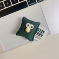 Macro view of dark green plush monster phone stand with big eyes and yellow puff ball - Pillow Face / Dark Green