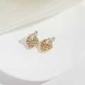 Nahaufnahme herzförmiger Goldohrringe mit Zirkonia-Mikropavé auf weißem Seidenstoff - Pave-Herz-Stil (Gold)