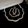 Detailopname van zilveren golvende ketting en oorbellen met fonkelende kristallen - Goud (3-delige set)