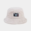 Détail d'un chapeau bob beige en fausse fourrure avec écusson de caméra rétro et cœur - Beige