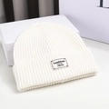 Gedetailleerde gebreide textuur van witte wintermuts met een modern geweven label - 56-58cm / Broken Wit