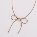Detalle de collar con lazo de oro rosa con cadena de serpiente y elegante colgante caído - Oro rosa