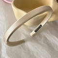 Detail of a thin champagne satin headband with soft sheen and smooth fabric texture - Apricot