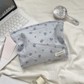 Close-up of light blue floral makeup bag with Sozakka brand label on a soft fabric background - Blue Rose Polyester