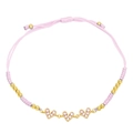 Detailed view of pink woven bracelet with three golden heart charms and pink zircon stones - Pink