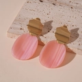 Detail of pink resin pendant earrings with gold wavy metal and marble texture accents - Pink