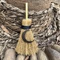 Detailed close-up of a mini witch broom with a crescent moon pendant in a forest setting - Black Moon