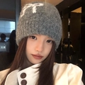 Dark grey knitted beanie featuring a large white bow jacquard pattern and fuzzy texture - Bow Pattern / Gray