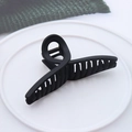 Matte black crisscross hair claw clip displayed on a minimalist white circular tray - Matte Cross Black