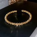 Makroaufnahme einer goldfarbenen geometrischen Manschette mit Kugelenden - Gold