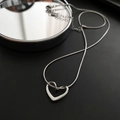 Primer plano de collar con colgante de corazón plateado sobre fondo oscuro y reflejo - 04-I14 Collar de Corazón de Acero de Titanio Plata
