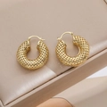 Orecchini a cerchio dorati con trama a rete su un cuscino per gioielli beige - Oro 18K / Oro