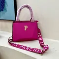 Detailed view of fuchsia lychee-grain tote featuring a gold P-logo and wide woven strap - Rose Red