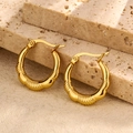 Close-up of textured gold-tone stainless steel hoop earrings on a beige stone - Twisted Spiral Texture Style (Style 6)