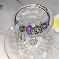 Close-up of silver star charm and dreamcatcher pendant on a purple bead charm bracelet - Purple
