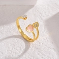 Goldener Titanring mit rosa Herz und Kleeblatt-Diamantfassung auf weißem Hintergrund - Gold
