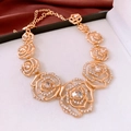 Close-up of a gold rose flower necklace with rhinestones on red silk fabric - Necklace - Gold