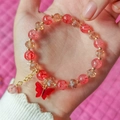 Details von rotem Perlenarmband mit Schmetterling-Anhänger und goldener Kette - Rot