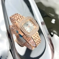 Close-up of a luxury rose gold square watch with diamond bezel on a reflective surface - Rose Gold White