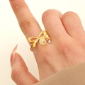Anello aperto dorato a forma di fiocco con perla centrale indossato al dito - Anello con perla e fiocco bianco placcato oro 18K (2008)
