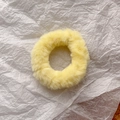 Close-up of a fluffy bright yellow faux fur scrunchie on textured paper background - Yellow
