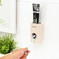 Wall-mounted beige automatic toothpaste dispenser with ecoco logo on white tile wall - Toothpaste Squeezer / Beige