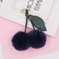 Detail of plush cherry keychain with navy fur balls, green faux leather leaves and gold clasp - Spring Ring / Navy Blue