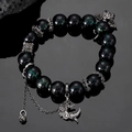 Close-up of beaded dragon bracelet with green ghost stones and silver charms - Antique Silver Dragon