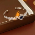 Macro detail of silver-tone open cuff bracelet with blue zircon clover eye design - Cuff Bracelet / Silver