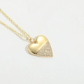 Macro shot of gold heart pendant with half-paved rhinestones on white texture - White Zirconia Heart-Shaped Style (XL3123)