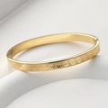 Vista dettagliata del bracciale in acciaio al titanio dorato con motivi a onde incisi - Oro