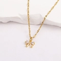 Détail d'un pendentif papillon doré avec oxydes de zirconium posé sur une pierre blanche - Style 6-Noeud Papillon Minimaliste Doré