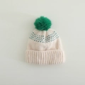 Detail of winter knit hat with fluffy green pompom and jacquard pattern on cream base - 3-10 Years / Green