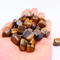 Polished natural Tiger Eye stones held in hand showing golden brown chatoyant texture - Tiger Eye Stone Bracelet