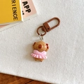 Detail of Capybara keychain in pink dress placed on white textured fabric for gifts - Pink Skirt Style