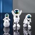 Set di 3 statuette di astronauti bianchi in varie pose con visiere colorate riflettenti - Un Set Sfumato