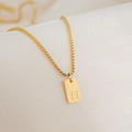 Macro detail of 18K gold plated rectangle pendant featuring an engraved letter H on box chain - Letter H