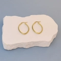 Close-up of golden hoop earrings with diagonal texture engraving on a stone display - Textured Oval Gold 3cm